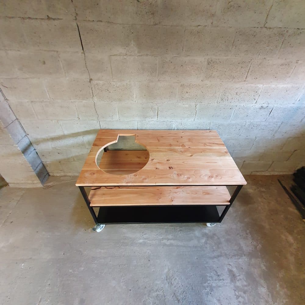 Bovenaanzicht van een bbq-tafel die in een werkplaats staat. Er zit een gat in het hout waar de bbq in kan.