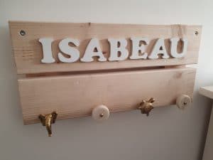 Kinderkapstok gemaakt van licht hout met daarop 4 haakjes en de naam Isabeau