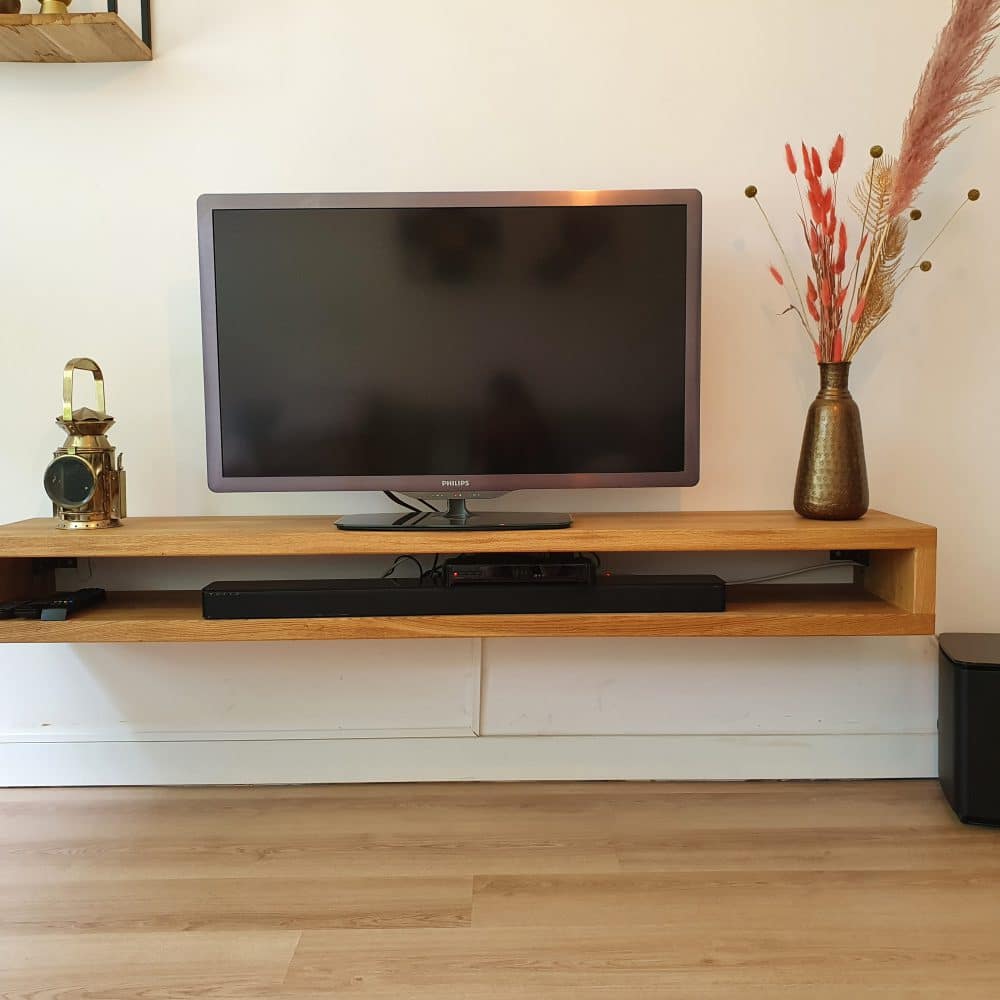 overzichtsfoto van een tv-meubel dat zweeft aan de muur, met daarop een lamp en een vaas